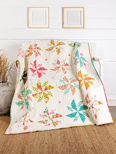 a quilted blanket sitting on top of a wooden floor next to a potted plant