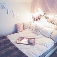 a white bed with pillows and lights on the headboard is shown in this bedroom