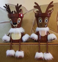 two brown and white christmas decorations sitting on top of a wooden shelf next to each other