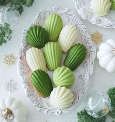 some green and white cookies are on a plate next to other holiday decorations, such as pine cones