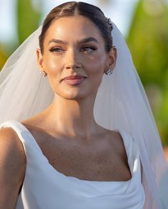 a woman in a wedding dress and veil looking off to the side with her hand on her hip