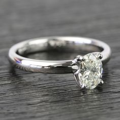 a close up of a diamond ring on a wooden surface