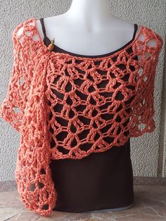 an orange crocheted shawl on top of a mannequin