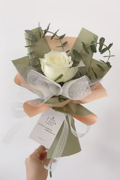 a person holding a bouquet of flowers with ribbons around it and tags attached to the stems