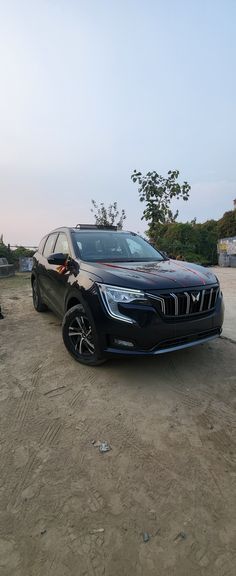 a black car parked on top of a dirt field