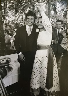 a man and woman standing next to each other in front of a table full of people