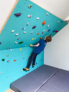 a young boy climbing up the side of a wall with his feet on an exercise mat