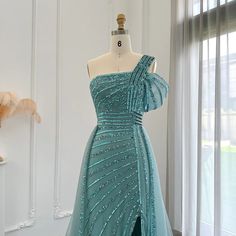 a dress on display in front of a window with sheer drapes and beading