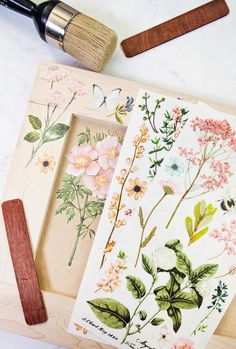 some flowers are sitting on a table next to a paintbrush and paper cutting board