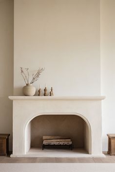 a white fireplace with some vases on top of it