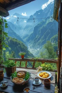 a wooden table topped with plates of food on top of a lush green forest covered hillside