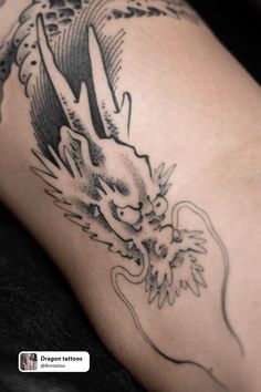 a close up of a person's leg with a dragon tattoo on the side