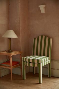 a green and white striped chair next to a small table with a lamp on it