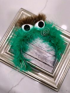 a close up of a stuffed animal with fake eyes and green feathers on it's head