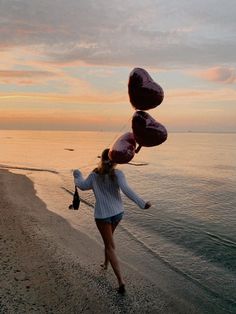 a woman walking on the beach with some balloons in her hair