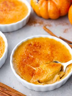 three small white bowls filled with pumpkin puree and cinnamon sticks next to some mini pumpkins