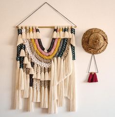 a wall hanging with some tassels and a hat on the wall next to it