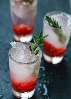 two glasses filled with ice and garnish on top of a black countertop