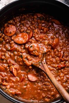 beans and sausage in a pot with a wooden spoon