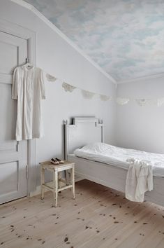 a white room with a bed and clothes hanging on the wall