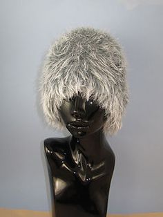 a black mannequin head with a fur hat on it's head, sitting on a wooden table