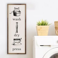 a wash dry sign hanging on the wall next to a washing machine and potted plant