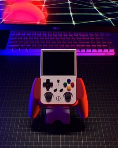 a game controller sitting in front of a computer keyboard with neon lights on the background