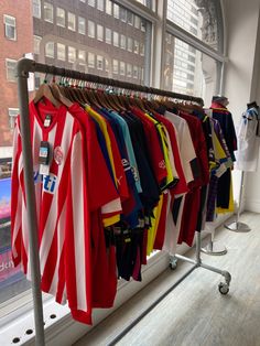 several shirts are hanging on a rack in front of a window