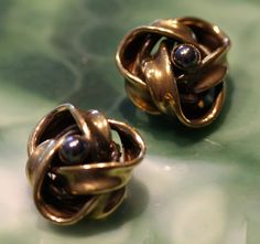 "Offered here are a beautiful pair of Ermani Bulatti earrings. Done in mixed goldtone metal, free formed to nest a black pearl like Hematite accent stone. Earrings are in fine vintage condition. They present a bold modern look and are approximately 1 \" in diameter. This unique look is ideal for any occasion. NOTE: We are happy to ship to our friends around the globe. Please contact us with any questions or concerns." Retro Metal Drop Clip-on Earrings, Luxury Mid-century Clip-on Earrings, Anniversary Vintage Clip-on Earrings With Polished Finish, Vintage Multicolor Round Clip-on Earrings, Vintage Multicolor Drop Clip-on Earrings, Black Pearl, Vintage Art Deco, Designer Earrings, Clip On Earrings