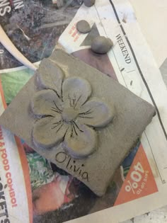 a stone with a flower on it sitting on top of some newspaper and other items