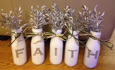 four white jars with silver leaves and the word faith painted on them are sitting on a wooden table