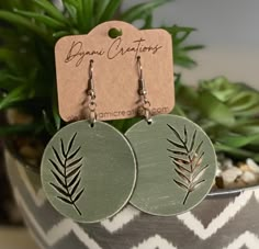 the earrings are made from wood and have green leaves on them, along with a tag that says organic creations