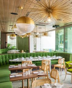 the interior of a restaurant with green booths and gold chandeliers hanging from the ceiling