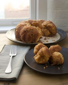 two plates with pastries on them next to a fork and napkin near a window