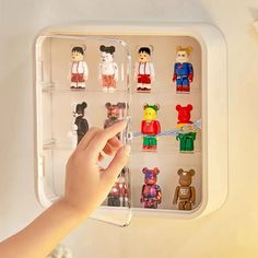 a hand is reaching into an open refrigerator with many small toy figures in the door