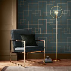 a chair and lamp in front of a blue wall with gold geometric designs on it