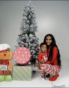 a woman and her baby are posing in front of christmas decorations with a teddy bear