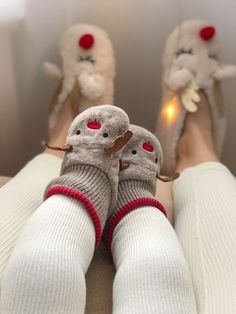 two feet wearing slippers and socks with stuffed animals on the bottom one has red eyes