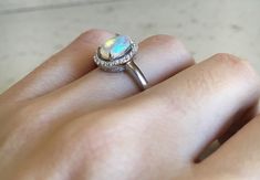 "A lovely Halo Setting featuring an oval shaped natural Fire Opal embellished with pave set cubic zirconia in Sterling Silver. Wrapped in a box ready for gift-giving. Ring Info ---------------------------------- Opal measure 6mm x 8mm Opal with Halo measure 11.5mm x 10mm Ring Shank Width 1.6mm Ring with Stone height 5.5mm HOW TO CARE FOR YOUR OPAL --------------------------------------------- Opals are soft and fragile gemstones, great care must be taken to avoid damaging it. Please refrain from Silver Opal Ring With Diamond, Oval Shape, Adjustable Nickel-free Opal Ring For Anniversary, Silver Opal Ring Nickel-free For Gift, Elegant Multi-stone Opal Ring With Oval Cabochon, Opal Promise Ring, Adjustable Opal Crystal Ring, Oval Shape, Rose Gold Opal Ring, Opal Wedding, October Birthstone Rings