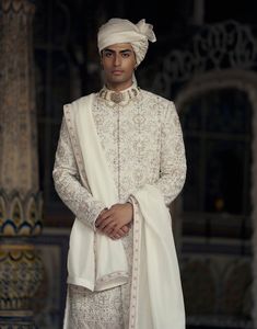 Embrace classic elegance in this ivory and beige raw silk sherwani, adorned with tonal resham embroidery and highlighted with dabka, beads, and crystals. Accompanied by a cotton silk kurta and churidar, it comes with a worked belt and stole. Luxury Designer Sherwani In Georgette, Luxury White Sherwani With Zari Work, Luxury Traditional Sherwani With Chikankari Embroidery, Luxury Ceremonial Chanderi Sherwani, Luxury Beige Chikankari Embroidered Bandhgala, Luxury Designer Off White Sherwani, Luxury White Dabka Sherwani, Luxury White Sherwani, Cream Sherwani With Resham Embroidery For Eid