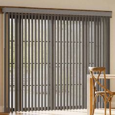 a dining room table and chairs in front of a sliding glass door with vertical blinds