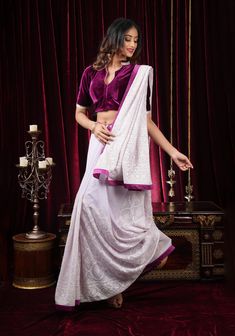 Set in a fluid georgette, this saree feautures self embroidery that is inspired by chikankari designs. The contrast satin trim in plum frames it with a pop of color and definition. The saree is ready with falls and pico done. An unstitched blouse fabric  is included. Note: The blouse that the model is wearing is for styling purposes only. The actual blouse piece that comes with the saree is the same fabric as the saree. The blouse that the model is wearing can be purchased separately from the blouse collection here - Designer Blouses Online Shobitam | Readymade Crop Tops for Women Note: There may be a slight difference in shade between the actual product and what you see on screen due to variance in screen settings and other factors. Note: This is a hand-made product. There may be minor in Elegant Purple Sets With Embroidered Border, Traditional Formal Saree With Chikankari Embroidery, Formal Saree With Embroidered Border, Purple Saree With Chikankari Embroidery, Bollywood Style Purple Blouse With Embroidered Border, Formal Purple Sets With Chikankari Embroidery, Purple Embroidered Georgette Blouse Piece, Purple Chanderi Blouse Piece With Embroidered Border, Designer Purple Saree With Chikankari Embroidery