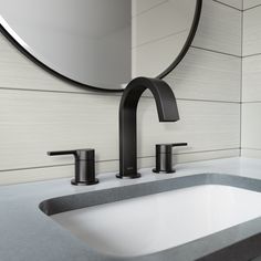 a bathroom sink with a black faucet next to a round mirror above it