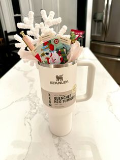 a coffee cup filled with candy and candies sitting on top of a white counter