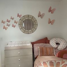 a bedroom with pink and orange decor on the wall, dresser and mirror in the corner