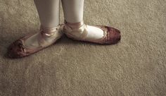 a person wearing ballet shoes standing on the floor