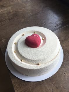 a white cake with a red heart on top