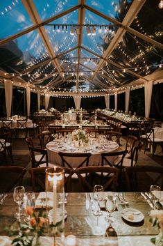 the inside of a tent with many tables and chairs set up for an outdoor dinner