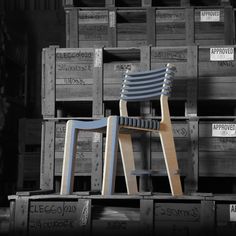 a wooden chair sitting on top of crates in front of a black and white background