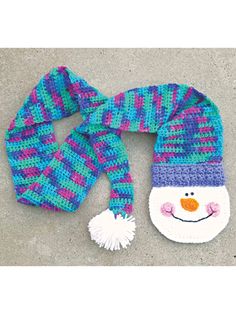 a knitted snowman hat and scarf on the ground